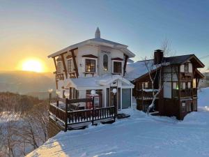 a house in the snow with the sunset in the background at Blueberry Apartment in Iiyama