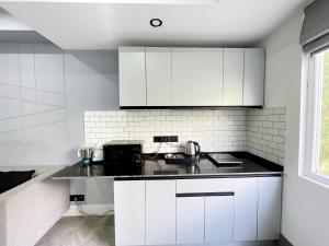 uma cozinha com armários brancos e um balcão preto em BedChambers Luxurious Serviced Apartment in Gurgaon em Gurgaon