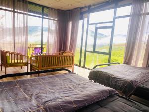 a bedroom with two beds and a large window at Ventosa Homefarm Măng Đen in Kon Von Kla