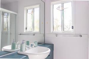 a white bathroom with two sinks and two windows at Kangaroo Cabin in Berrara