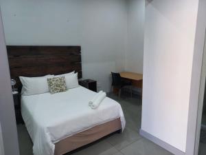 Schlafzimmer mit einem weißen Bett mit einem Kopfteil aus Holz in der Unterkunft Triple9 Hatfield Guesthouse in Pretoria
