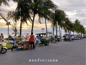 a group of people at a market with palm trees at Cozy House บ้านพักริมหาดบางแสน in Ban Bang Saen (1)
