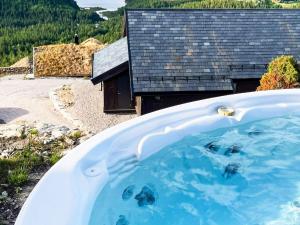 Holiday home Drangedal في Drangedal: حوض استحمام بالماء الأزرق أمام المنزل