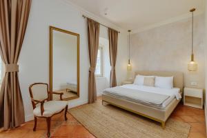 a bedroom with a bed and a mirror and a chair at Vila Perast Boutique Hotel in Perast