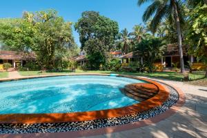 a swimming pool in front of a house at Granpa's Inn Hotel Bougainvillea in Anjuna