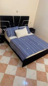 Bett mit blauer Bettdecke und Kissen in einem Zimmer in der Unterkunft Kornich in Nador