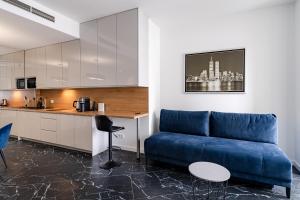 a living room with a blue couch and a kitchen at RentPlanet - Apartamenty OVO in Wrocław