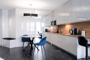 a kitchen with white cabinets and a table with blue chairs at RentPlanet - Apartamenty OVO in Wrocław