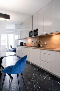 a kitchen with white cabinets and a blue chair at RentPlanet - Apartamenty OVO in Wrocław