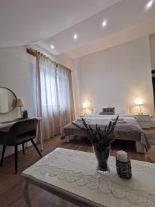 a bedroom with a bed and a desk and a table with a vase at Elysian Apartments in Grabovac