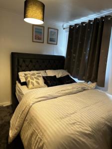 a bedroom with a large bed with black curtains at Lovely room in South London in Addington