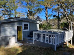 a small shed with a porch and a yellow door at Sunflower House, a cozy cabin at Lake Wentworth in Wentworth Falls