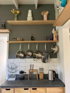 a kitchen with pots and pans hanging on the wall at Sunflower House, a cozy cabin at Lake Wentworth in Wentworth Falls