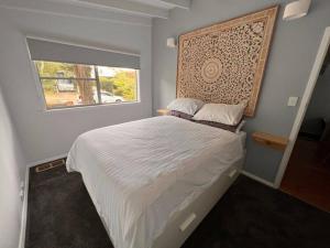 Un dormitorio con una cama grande y una ventana en Sunflower House, a cozy cabin at Lake Wentworth, en Wentworth Falls