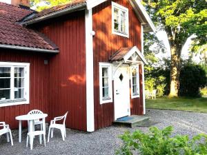 uma casa vermelha com uma porta branca, uma mesa e cadeiras em Holiday home Tystberga III em Tystberga