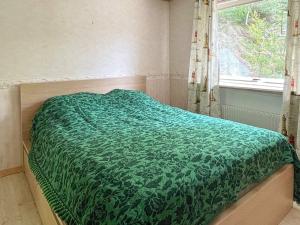 Cama con edredón verde en habitación con ventana en Holiday home VAREKIL VI, en Varekil