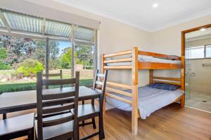 a bedroom with a bunk bed and a table and chairs at Braeside Cabin One Pinkwood in Central Tilba