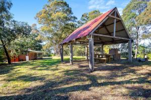 a picnic shelter with a bench in a park at Braeside Cabin One Pinkwood in Central Tilba