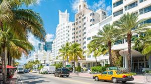 ein gelbes Taxi, das vor einem großen Gebäude eine Straße hinunterfährt in der Unterkunft 1 bedroom in the BEST location in South Beach ! in Miami Beach