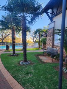 a park with two palm trees and a bench at Mooikloof Village Apartment with Solar Backup in Pretoria