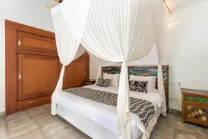 1 dormitorio con cama con dosel y cortinas blancas en Villa Cinta Umalas, en Canggu