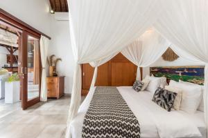 1 dormitorio con 1 cama blanca con cortinas blancas en Villa Cinta Umalas, en Canggu