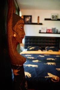 a wooden statue of a woman standing next to a bed at Jungle Stay in a Hidden Paradise in Zwijndrecht