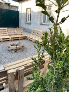 a group of wooden benches in a courtyard with a tree at Ayla Hostel in Osh