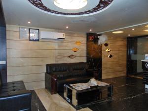 a lobby with a leather couch and a television at HOTEL REST INN in Surat