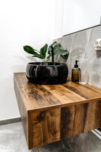 un lavandino nero da bagno con una pianta in vaso su un bancone in legno di Ego Apartments a Baile Felix