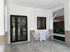 a white building with two chairs and a door at Cozy House บ้านพักริมหาดบางแสน in Ban Bang Saen (1)