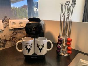 a coffee maker and two coffee cups on a counter at FamilienWohnung Wildspitze am Sonnenhang in Neukirchen am Großvenediger