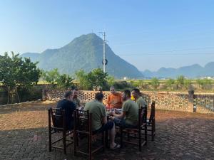 a group of people sitting around a table eating at Bac Son Homestay in Bắc Sơn