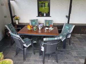 una mesa de madera con sillas y flores en un patio en Apartment with garden in a wooded setting, en Auw