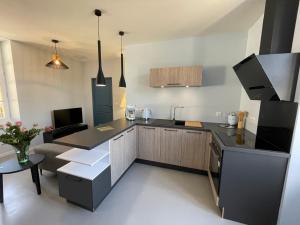 a kitchen with a black counter top and a living room at Gîte de Charme Jumelé pour 4 personnes in Cazals