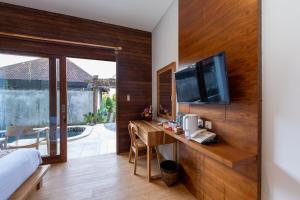 1 dormitorio con escritorio y TV en la pared en Paisa Ubud en Ubud