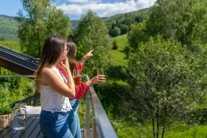 Duas raparigas numa varanda com copos de vinho. em Apartamenty Pod Gondolą - Mountain Resort Villa z sauną - Dream Apart em Szczyrk