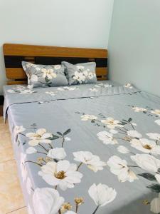 Una cama con una manta azul con flores blancas. en GM Homestay en Hai Phong