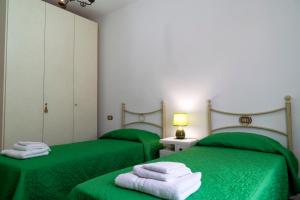 Habitación con 2 camas verdes y toallas. en CASA TERESA, en Loppeglia