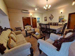 a living room with couches and a table and chairs at Shelton Dezire Lodge in Islamabad