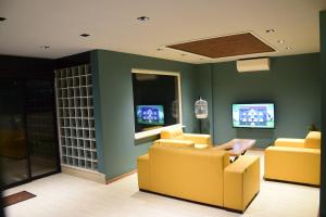 a living room with two yellow chairs and two televisions at KUZEY OTEL in Sinop