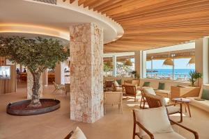 a lobby with a tree and tables and chairs at Universal Hotel Aquamarin in Sant Elm