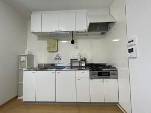 a white kitchen with a sink and a stove at 青梅森の宿 in Ome