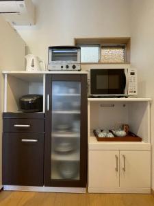 uma cozinha com um frigorífico e um micro-ondas em 青梅森の宿 em Ome