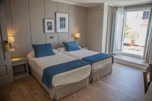 a bedroom with two beds and a large window at Hotel Doña Blanca in Jerez de la Frontera