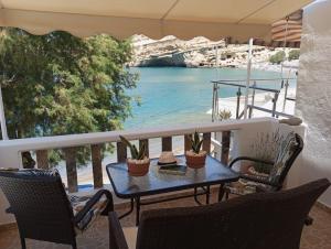 a table on a balcony with a view of the water at Seaside Nicola's Studio in Matala