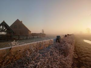 un granero en una granja en la niebla con una valla en 't Zuden van Aertrycke en Zedelgem