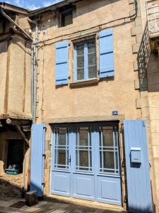 an old building with blue doors and windows at Le Quatorze, au cœur de Najac in Najac