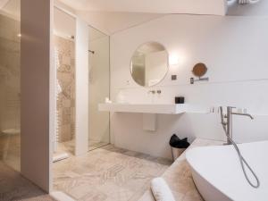 a bathroom with a tub and a sink and a mirror at Yndo Hôtel in Bordeaux