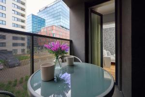 a glass table with a vase of flowers on a balcony at Gwiaździsta Apartment by the Sky Tower in Wrocław by Renters in Wrocław